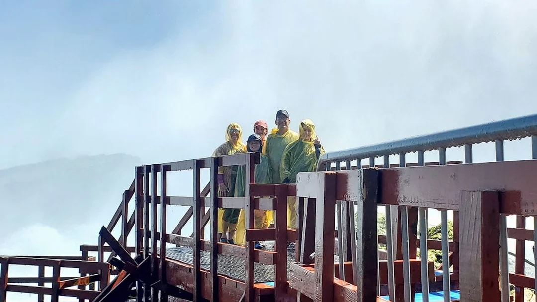 Visitors in rain ponchos on Cave of the Winds tour platform, Niagara Falls, New York.