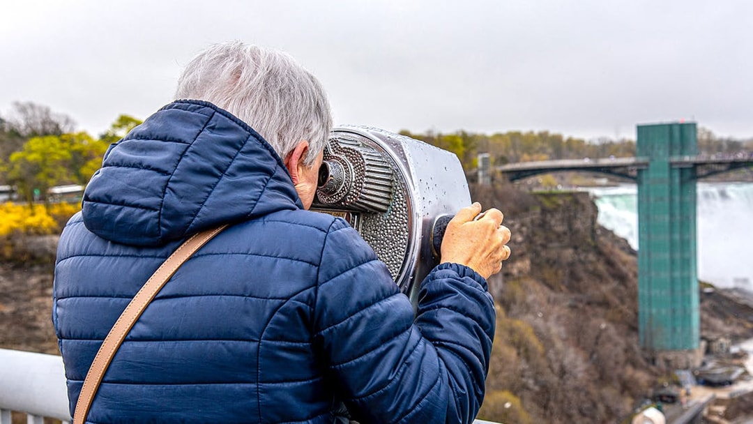 Person viewing Niagara Falls through binoculars on Maid of the Mist tour.