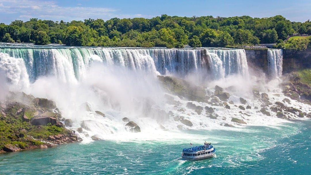 Boat approaching Niagara Falls with mist rising from the waterfall.