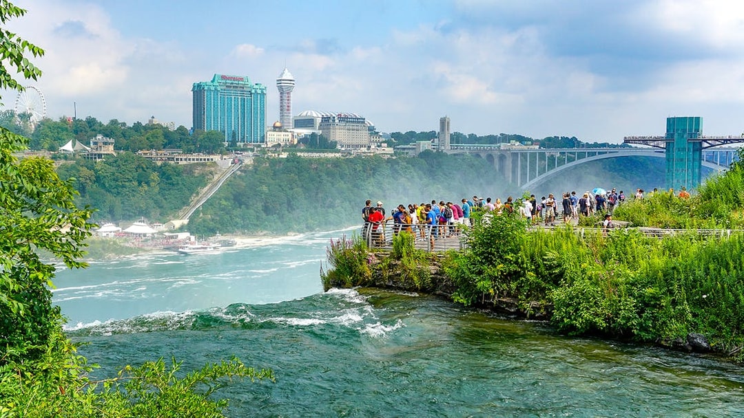 Tourists on Luna Island viewing Niagara Gorge through mist at Niagara Falls.