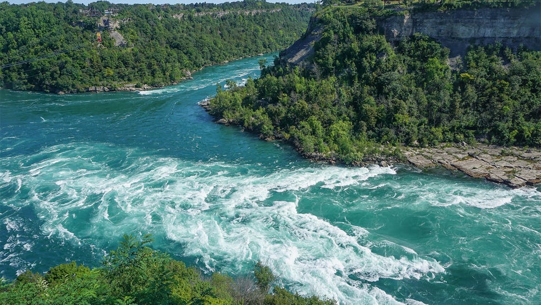 Whirlpool Rapids in Niagara River, surrounded by lush greenery, Ontario, Canada.