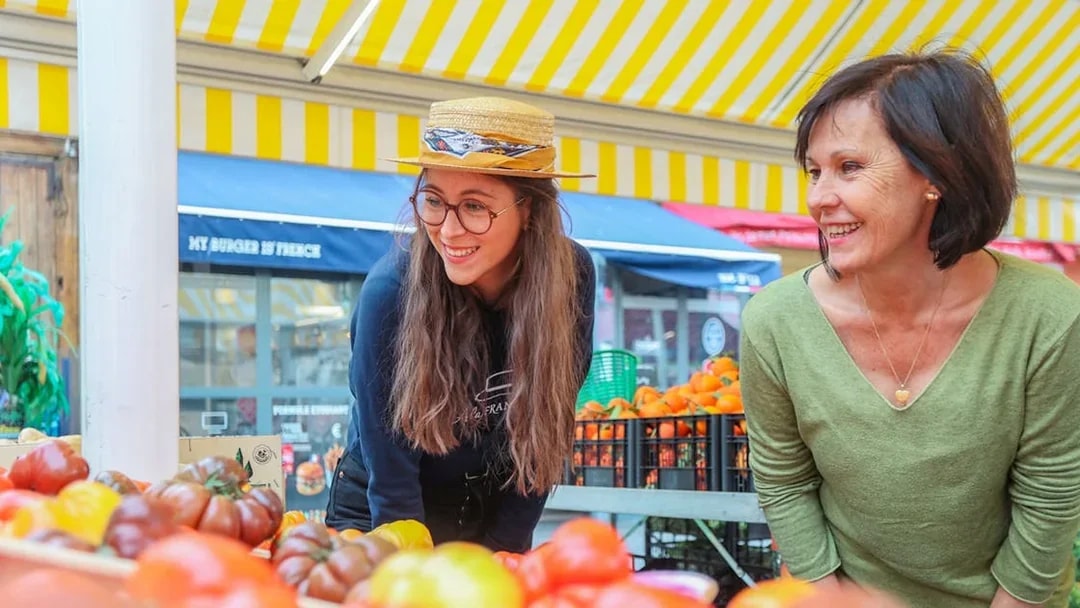 Women exploring a vibrant market in Nice during a walking and driving tour.