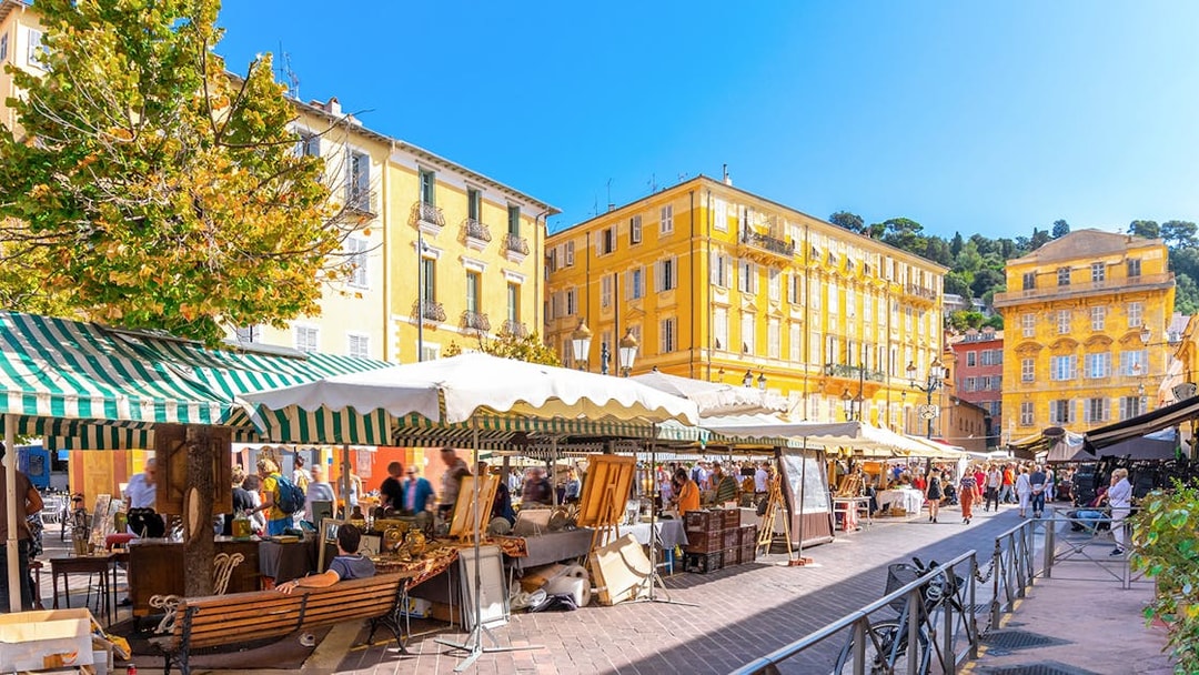 Cours Saleya Flower Market with stalls and yellow buildings in Nice, France.