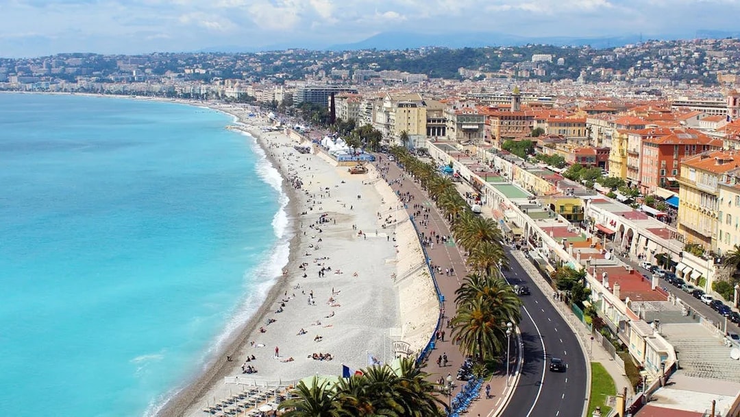 Promenade des Anglais in Nice with beachgoers and coastal view.