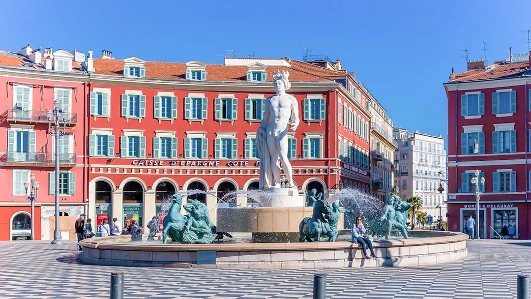 Fountain of the Sun in Place Masséna, Nice, with red buildings in the background.