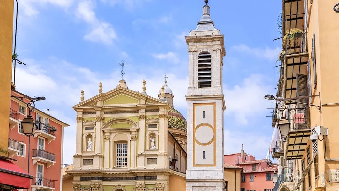 Saint Reparata Cathedral facade and bell tower in Nice, France, surrounded by colorful buildings.
