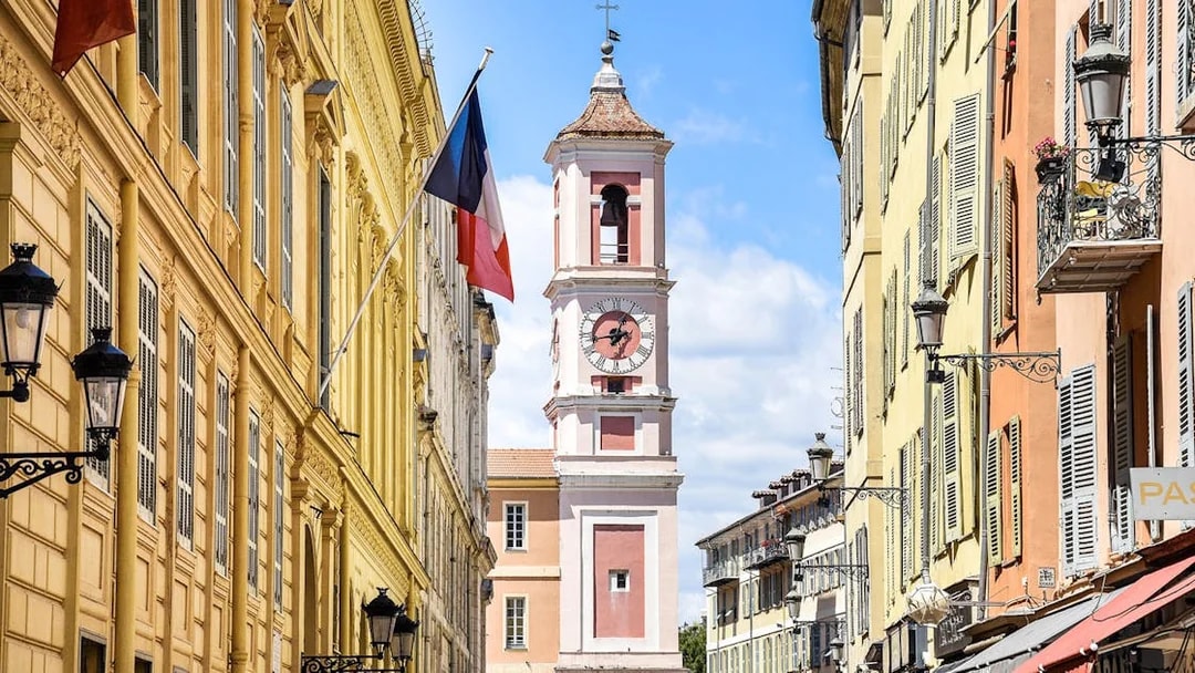 Clock tower on Rue Saint-François de Paule, Nice, France, with French flag.