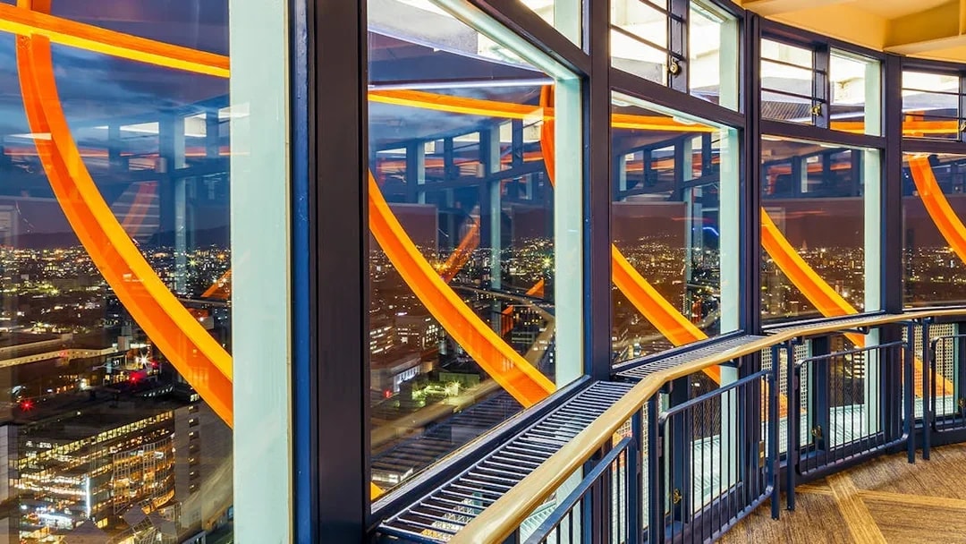 Kyoto Tower observation deck illuminated at night with city view.