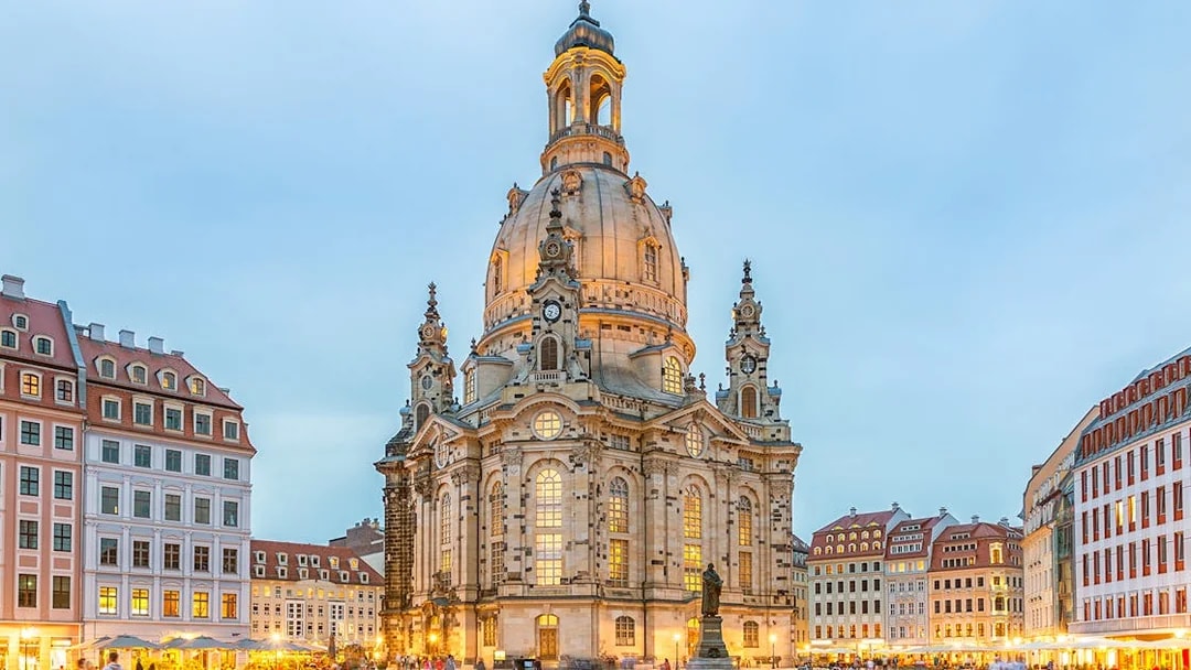 Frauenkirche in Dresden with illuminated dome and surrounding square at dusk.