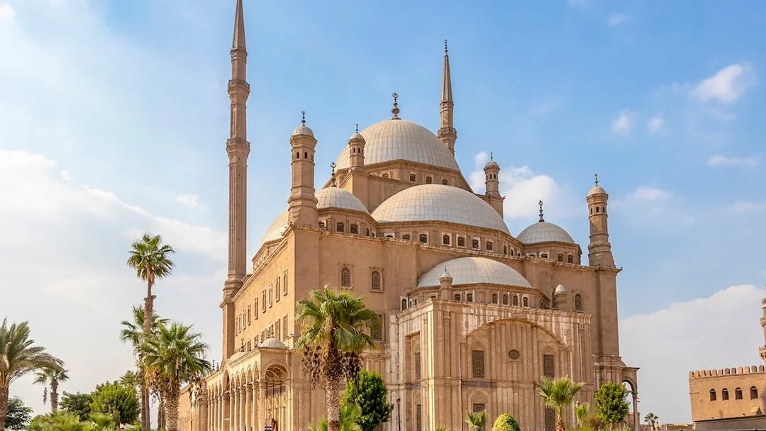 Citadel of Saladin in Cairo with palm trees and blue sky.