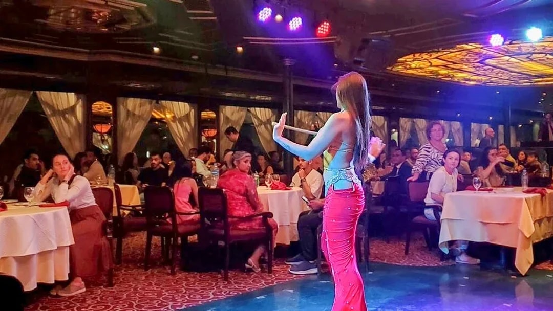 Belly dancer performing on a Nile River dinner cruise in Cairo with guests watching.
