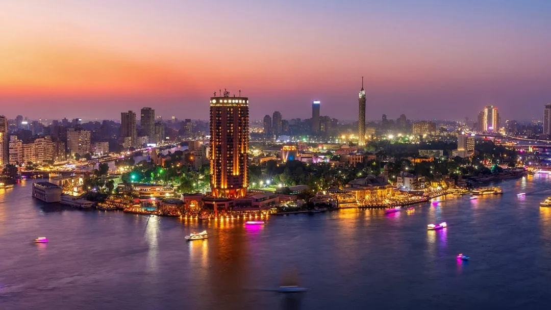 Cairo skyline at sunset with boats on the Nile River, highlighting a dinner cruise experience.