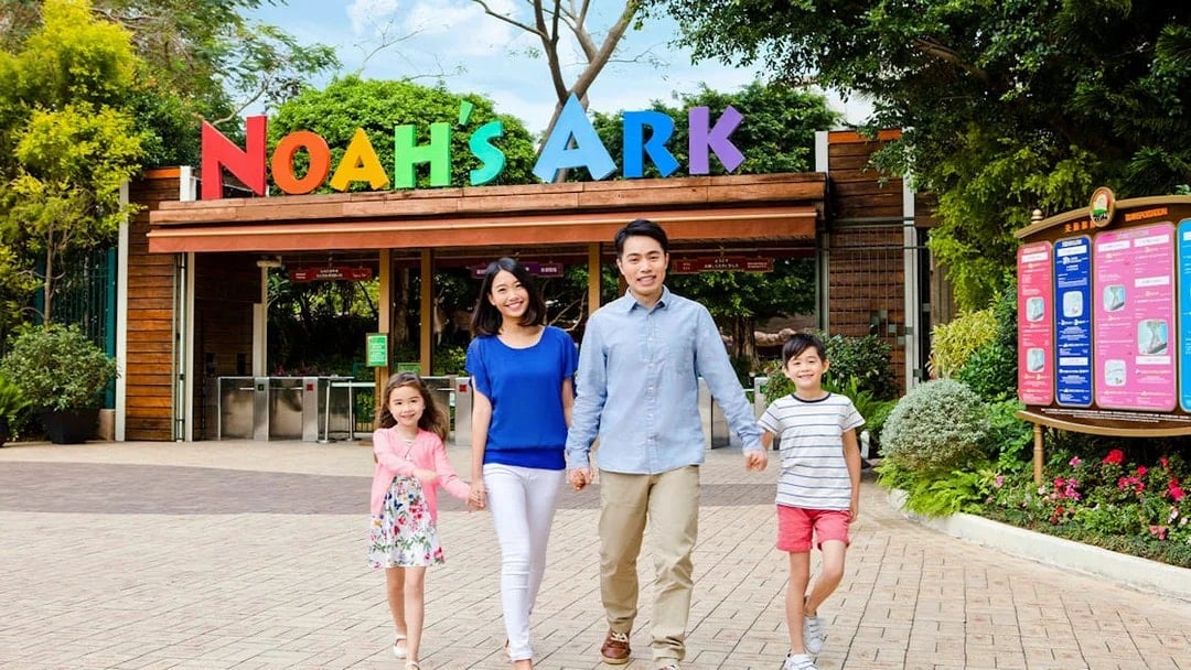 Family walking at Noah's Ark entrance, Hong Kong, with colorful sign above.