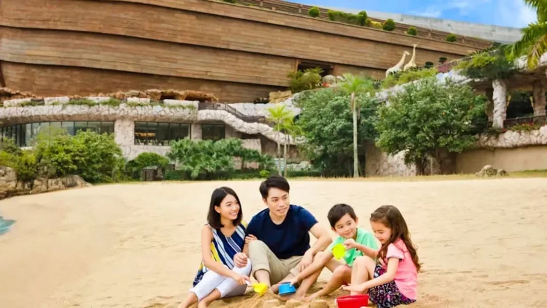 Family playing on the beach in front of Noah's Ark, Hong Kong.