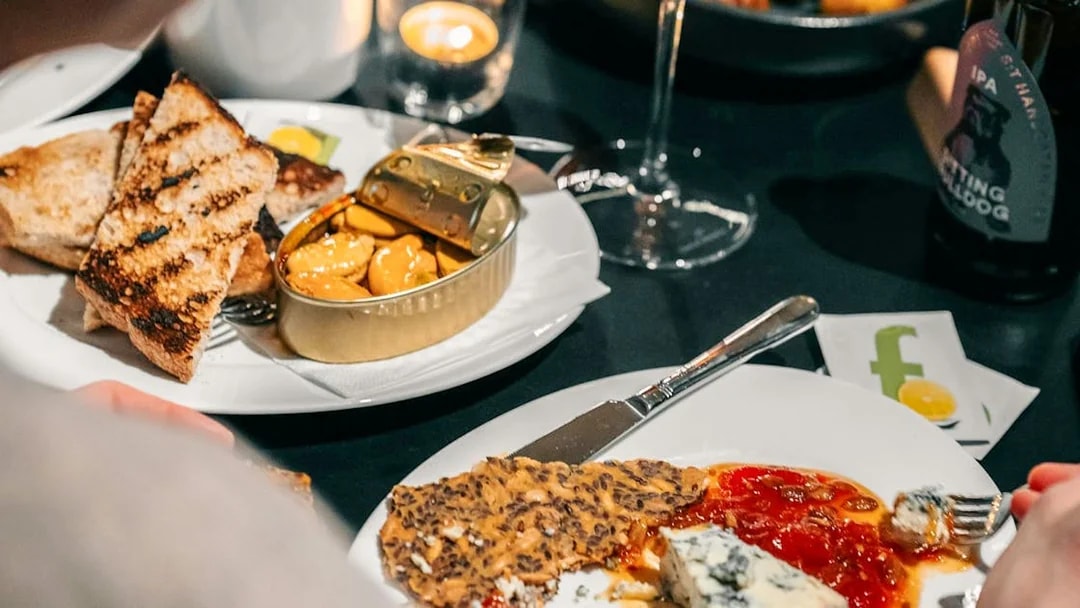 Dining experience at Nobel Prize Museum with cheese, crackers, and canned seafood.