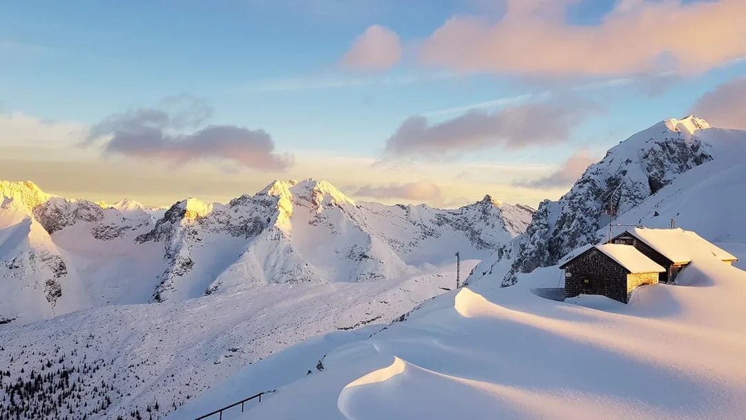 Snow-covered mountains and a cabin at sunset in Innsbruck, Austria.