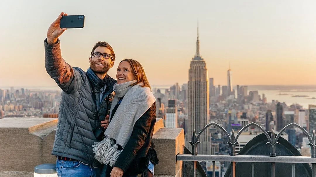 Couple taking a selfie with Empire State Building from Top of the Rock, New York City.