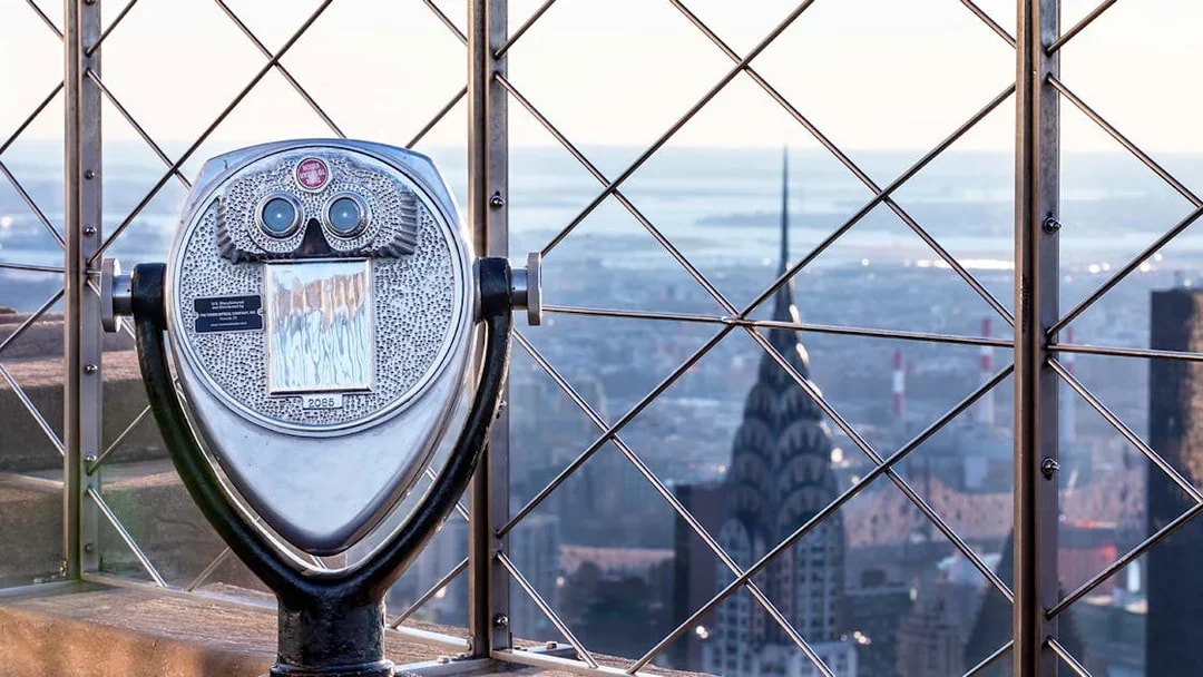 Observation deck binoculars overlooking New York City skyline from Empire State Building.