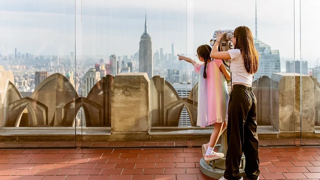 Children using binoculars at Top of the Rock, Rockefeller Center, with New York skyline.