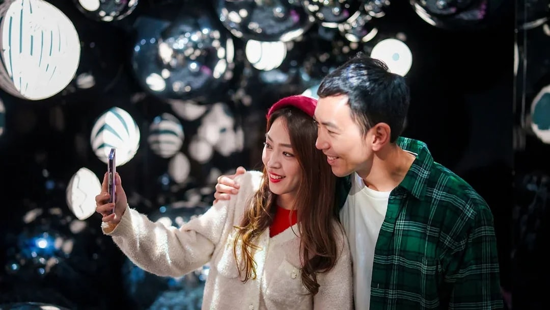 Couple taking a selfie at Ocean Park Hong Kong with reflective decor in the background.