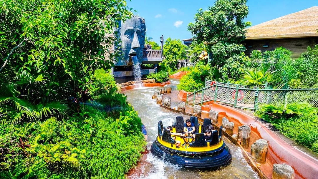 Raft on The Rapids ride at Ocean Park Hong Kong with waterfall and lush greenery.