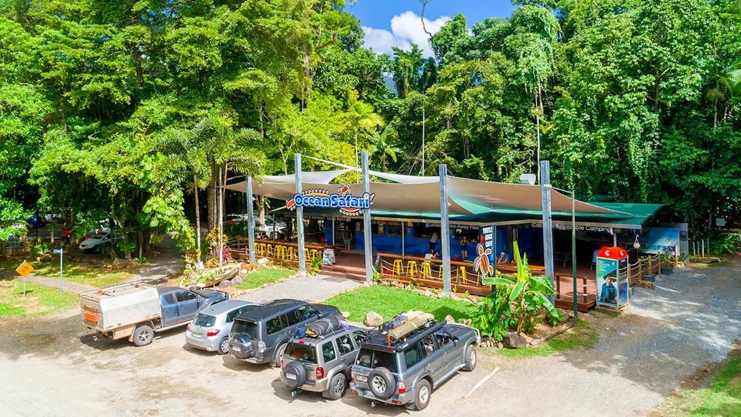 Ocean Safari Tour base with parked vehicles and lush greenery.
