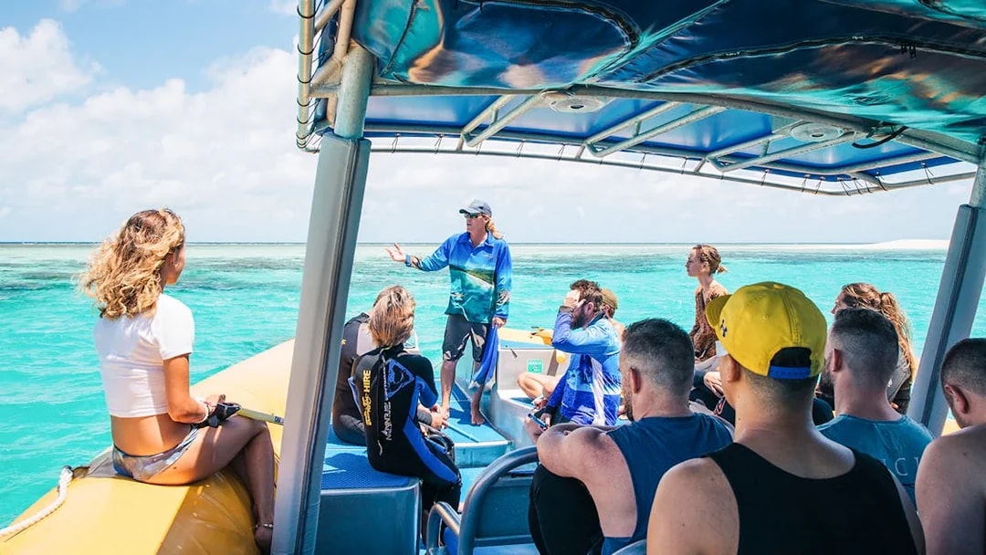 Tour group on a boat with guide during Ocean Safari Tour-9, exploring clear blue waters.