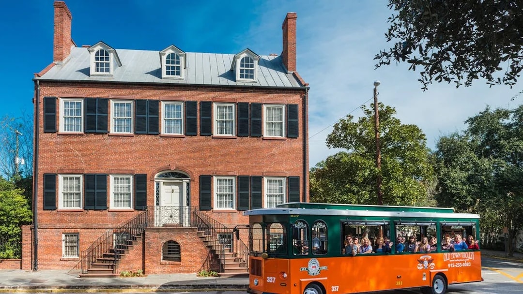 Savannah Old Town Trolley passing historic brick building.