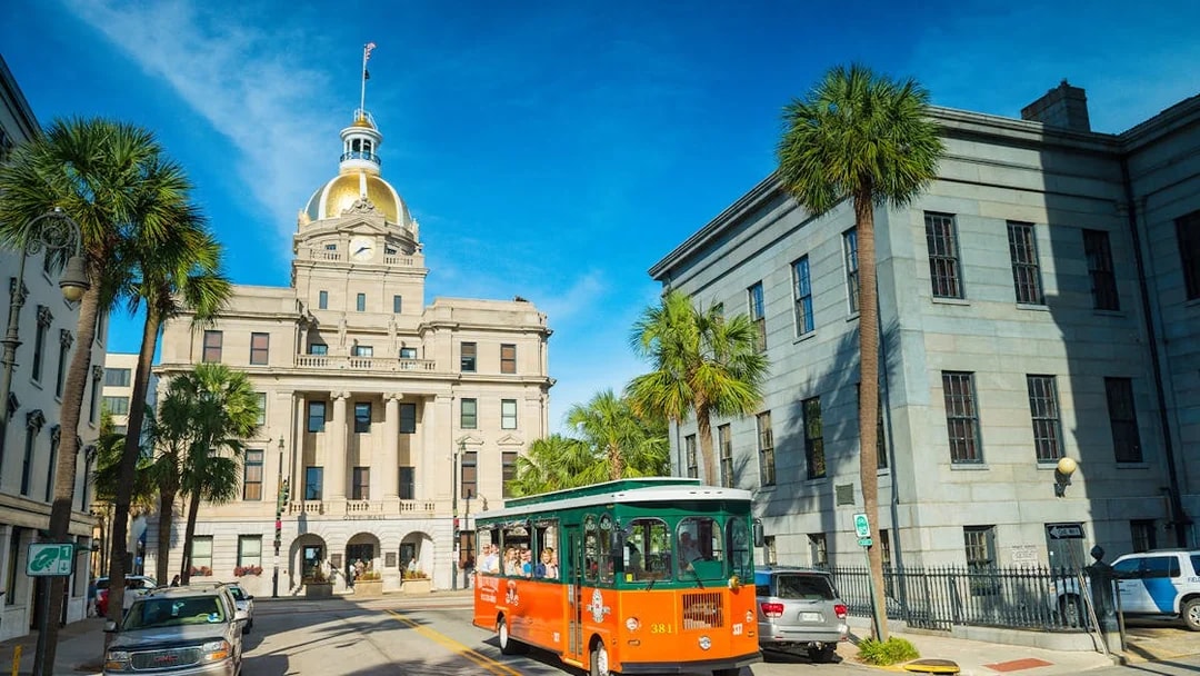 Savannah trolley passing City Hall with golden dome on sightseeing tour.
