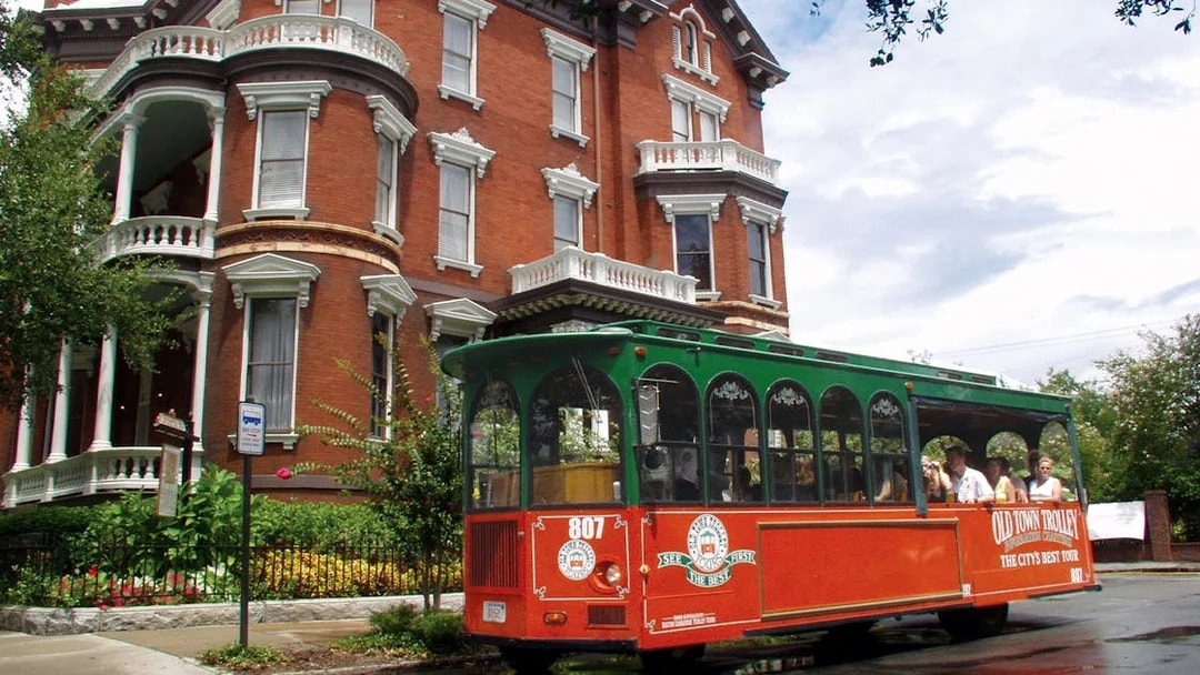 Savannah Old Town trolley passing historic brick building.