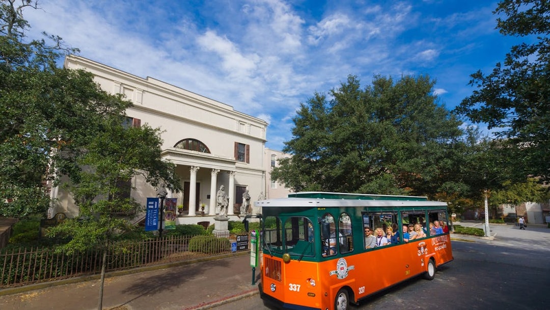 Trolley passing historic building on Savannah Old Town sightseeing tour.
