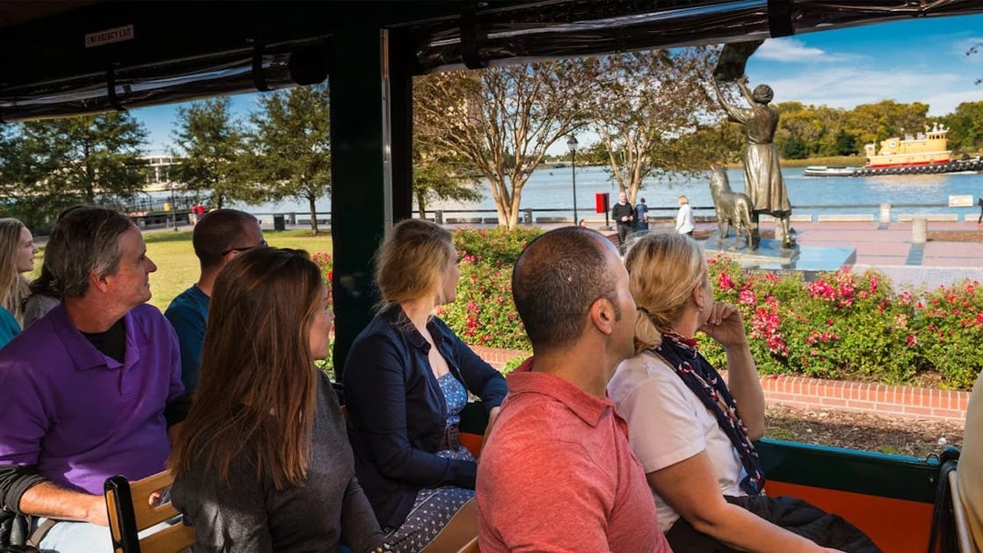 Tourists on Savannah Old Town Trolley viewing the Waving Girl statue by the river.