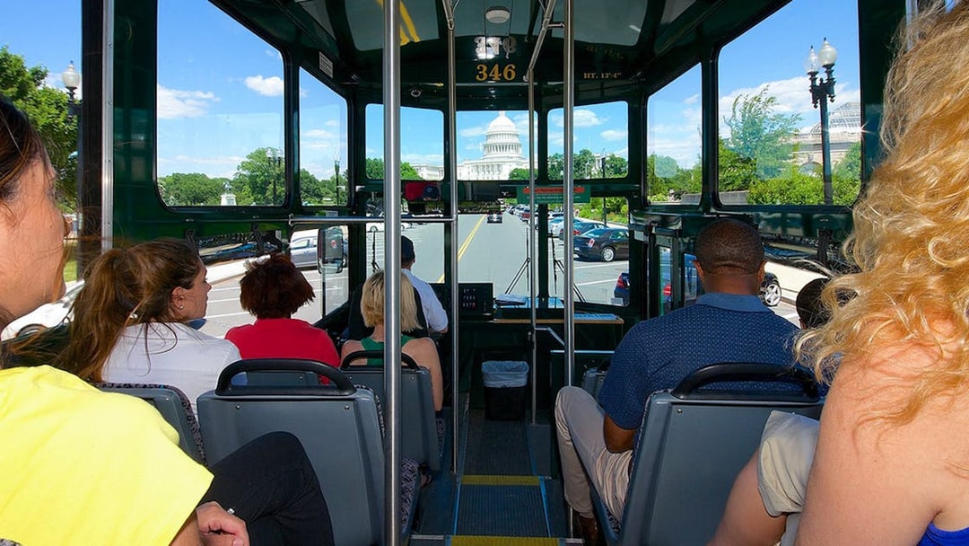 Tourists on a Washington DC hop-on hop-off bus with the Capitol Building in view.