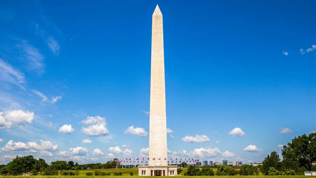 Washington Monument with flags, Washington DC, under clear blue sky.