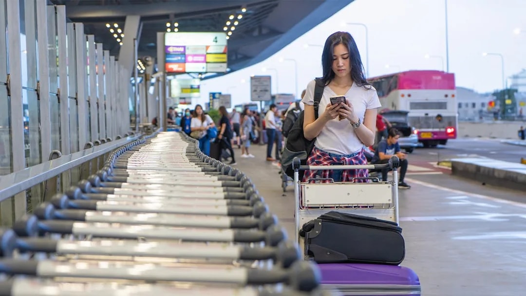 Traveler with luggage cart at Palermo Airport terminal.
