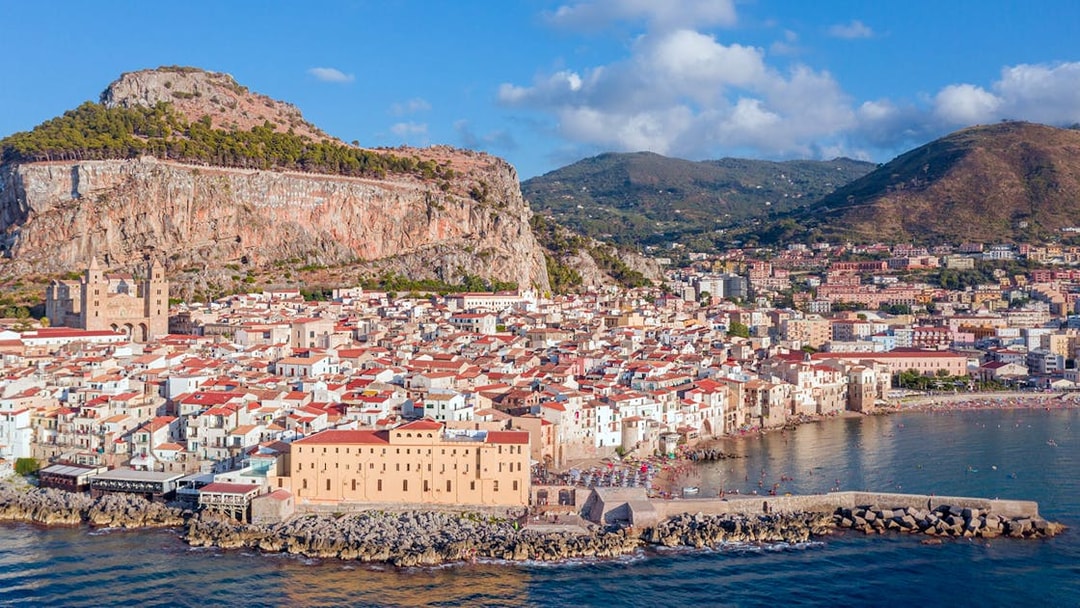 Aerial view of Palermo's coastline with historic buildings and mountains.