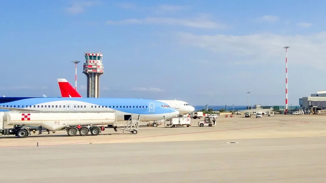 Palermo Airport runway with parked airplanes and control tower.