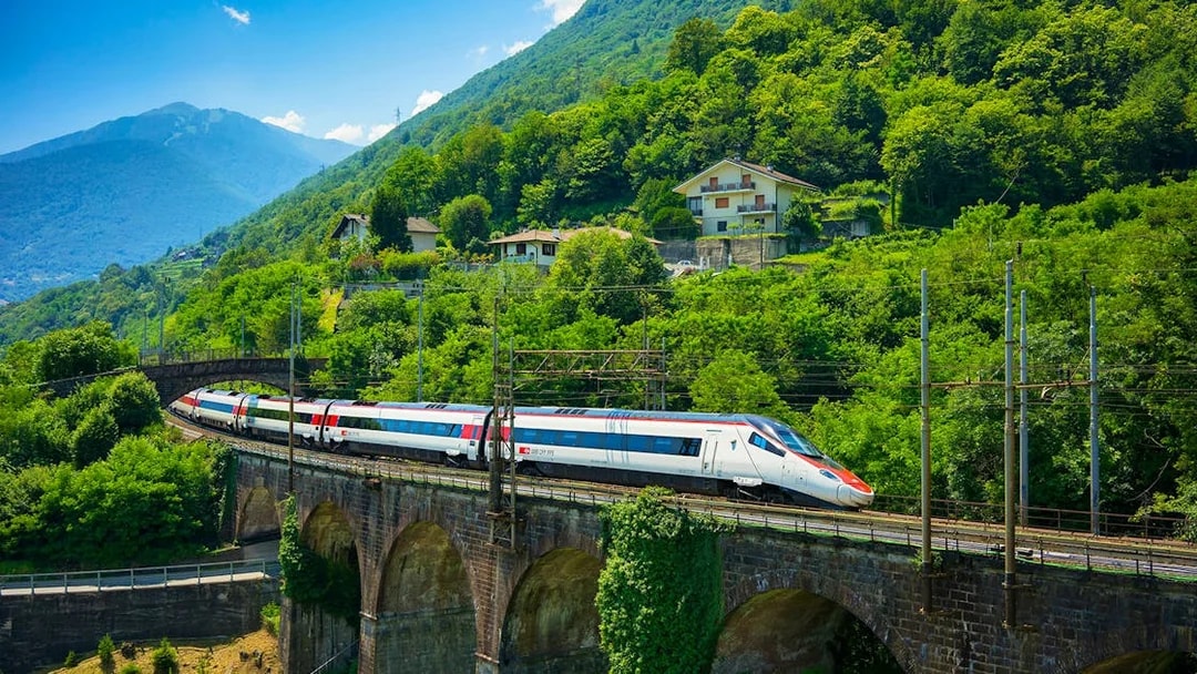 Train crossing a viaduct surrounded by lush greenery near Geneva, Switzerland.