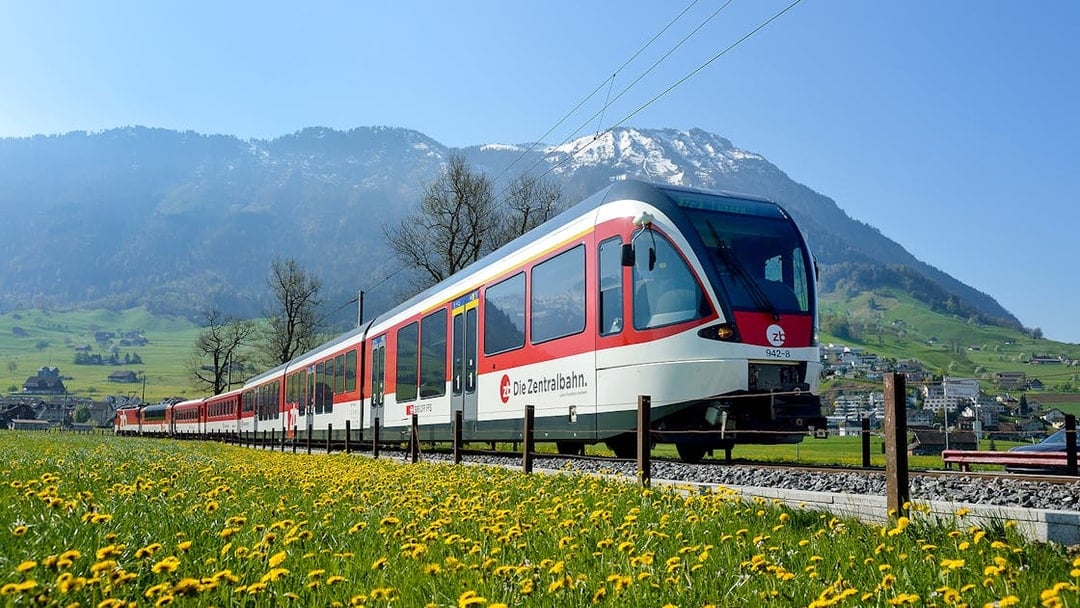 Train traveling through scenic landscapes near Lucerne, Switzerland with mountains in the background.