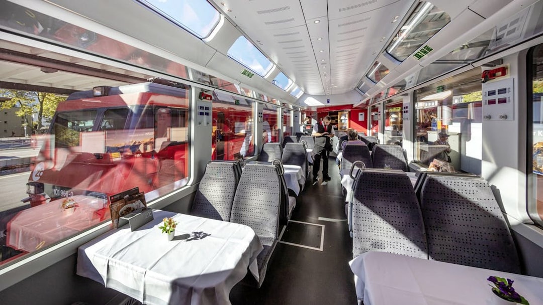 Interior of Lucerne–Interlaken Express train with dining tables and large windows.