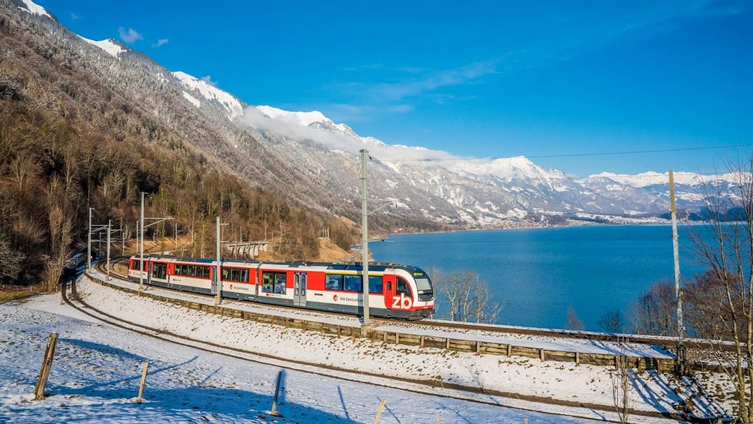 Train on Lucerne–Interlaken Express route with snowy mountains and lake views.