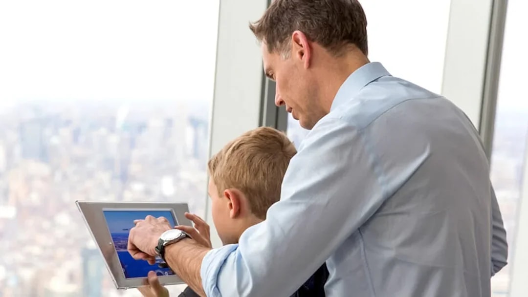 Father and son using a tablet at One World Observatory, New York City.