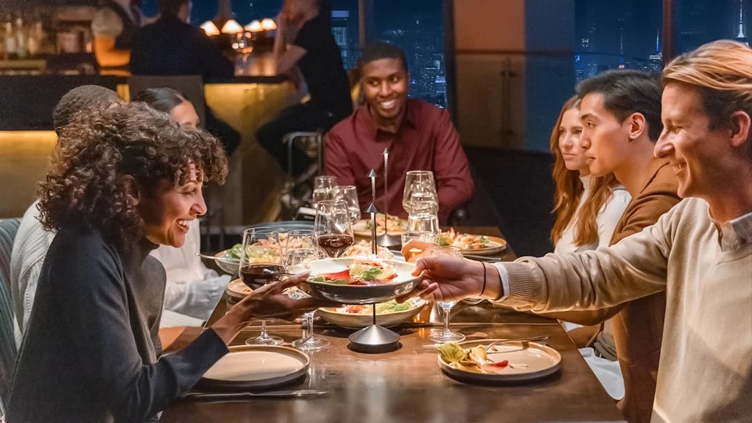 Group dining at One World Observatory with city skyline view.