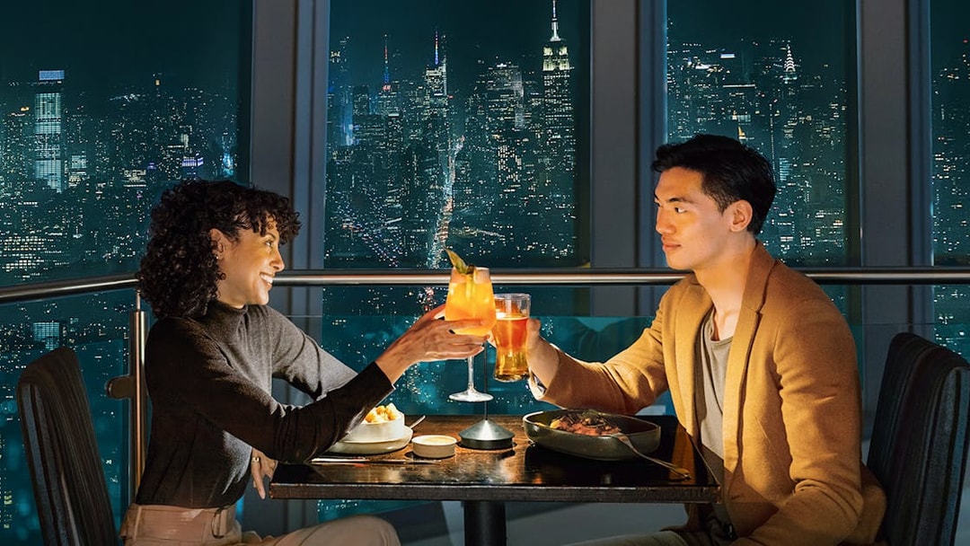 Couple dining with city skyline view at One World Observatory, New York City.