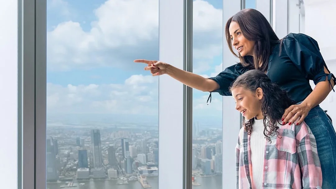 Tourists enjoying New York City skyline from One World Observatory's 100th-floor deck.