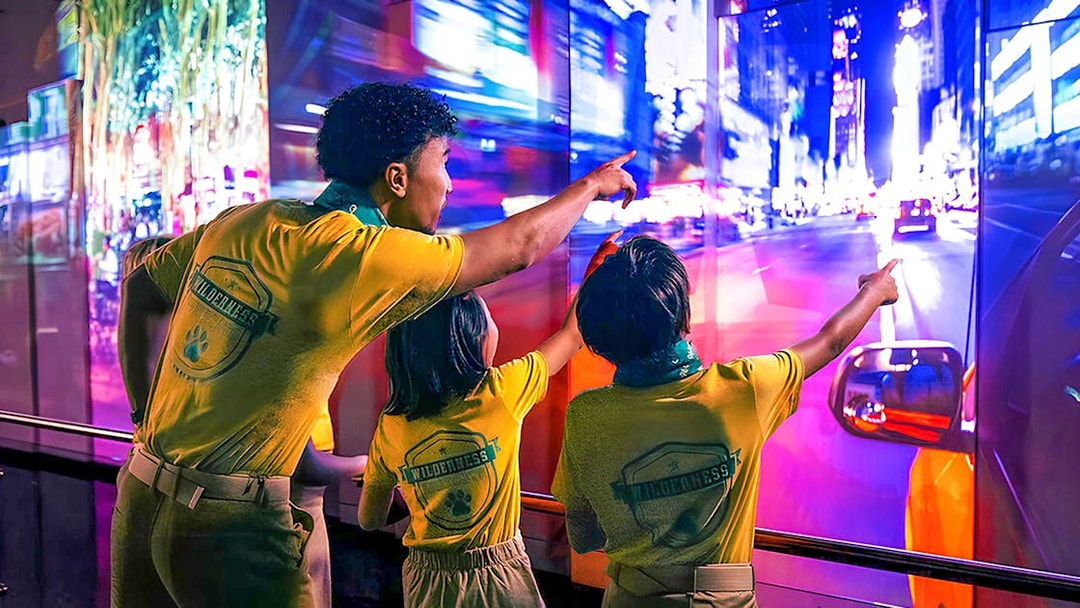 Visitors pointing at vibrant cityscape display at One World Observatory, New York.