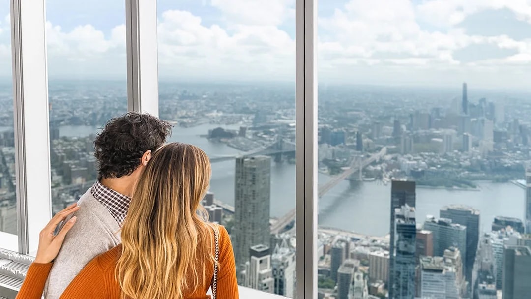 Couple enjoying panoramic views of New York City skyline from One World Observatory.