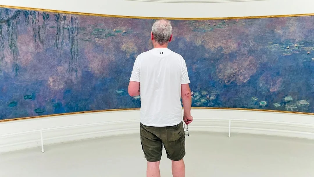 Man viewing Monet's Water Lilies at Orangerie Museum, Paris.