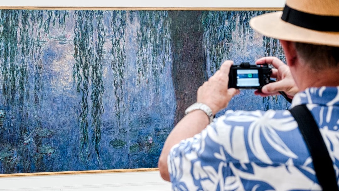 Tourist photographing Monet painting at Orangerie Museum, Paris.