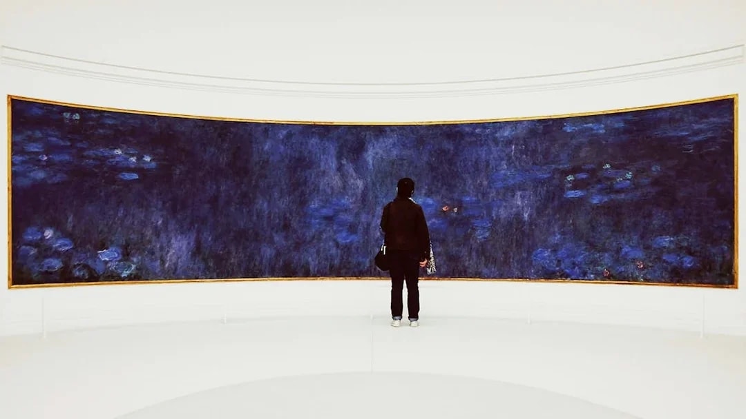 Visitor admiring Monet's Water Lilies at Orangerie Museum, Paris.